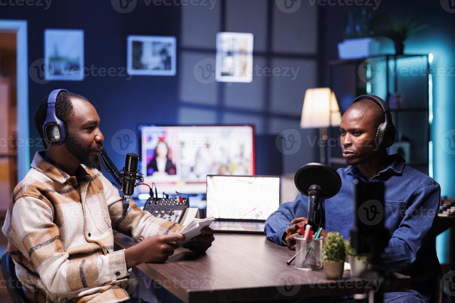 Male presenter recording live talk show using professional equipment at home. African American men speaking into microphones doing an online production, creating a podcast episode. photo