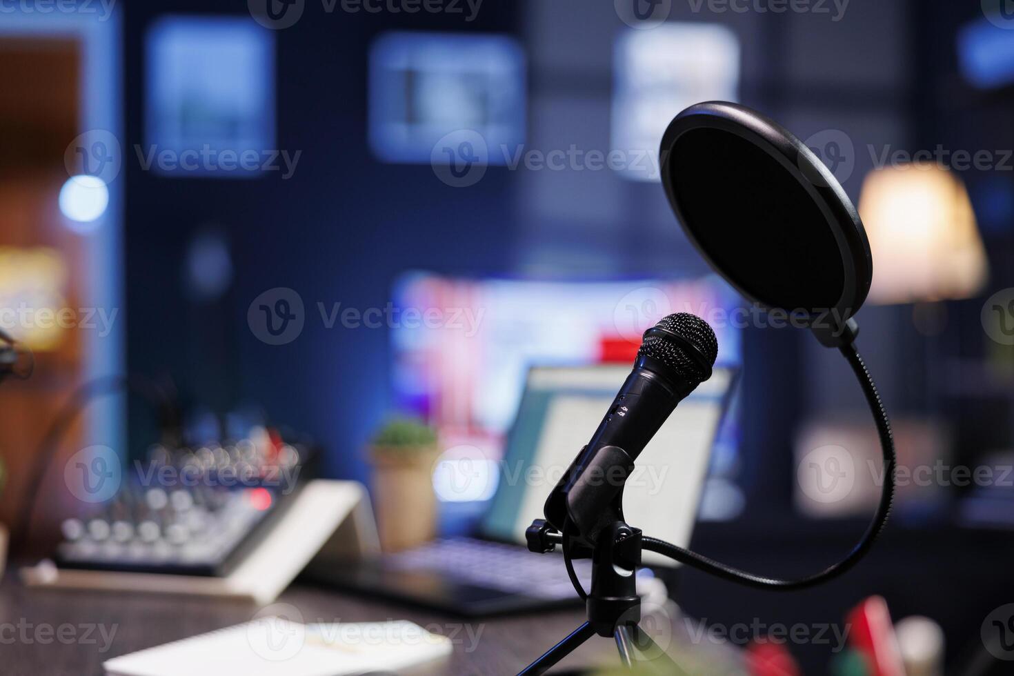 Closeup of a professional podcast microphone resting on a desk in a recording ready podcasting home studio. Selective focus of podcast equipment in empty room, ready to be used for online streaming platforms. photo
