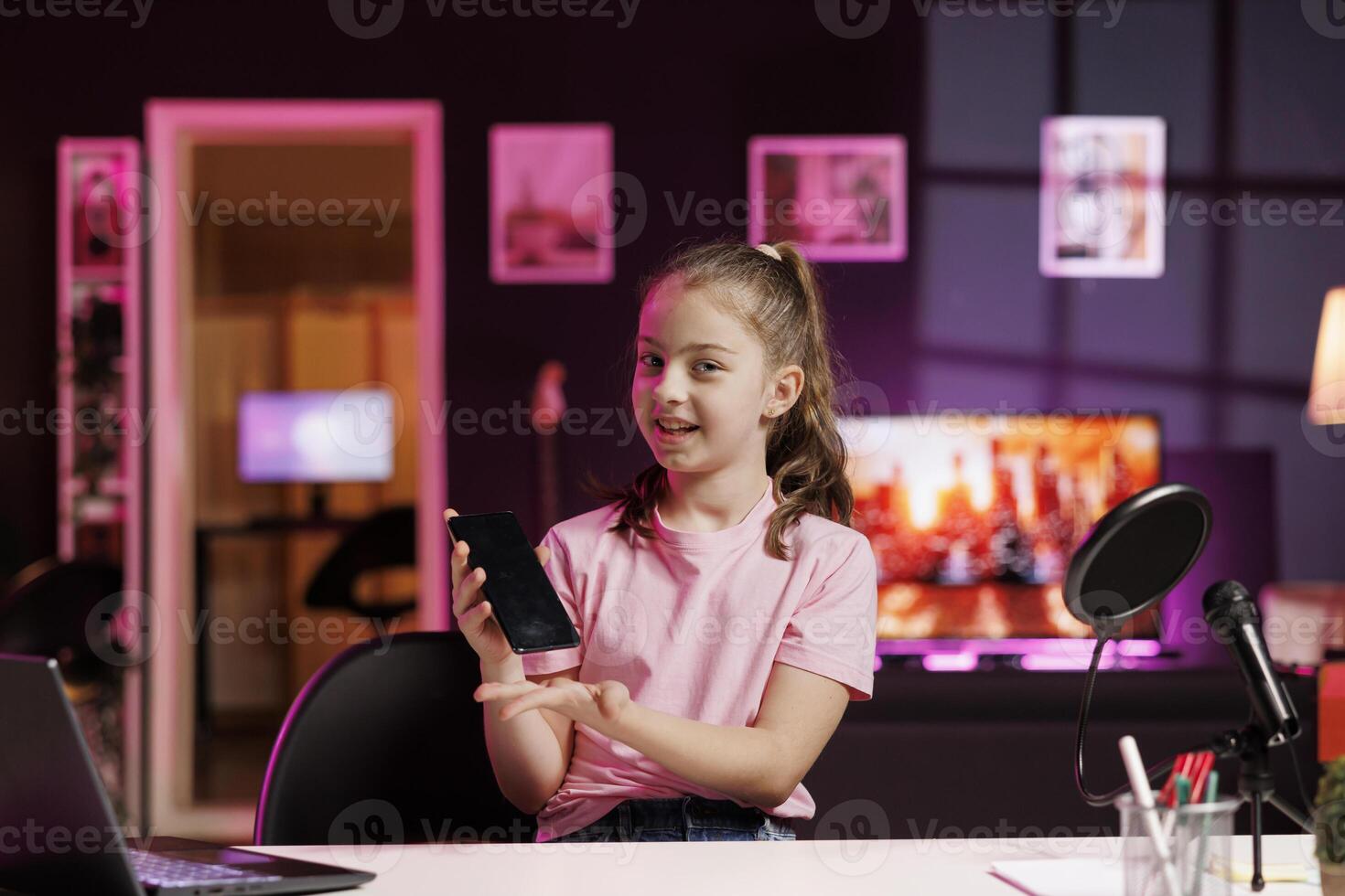 Smiling child filming assessing smartphone performance, talking about components used. Gen Z media star shoots mobile phone review for online channel, pleased with high quality materials photo