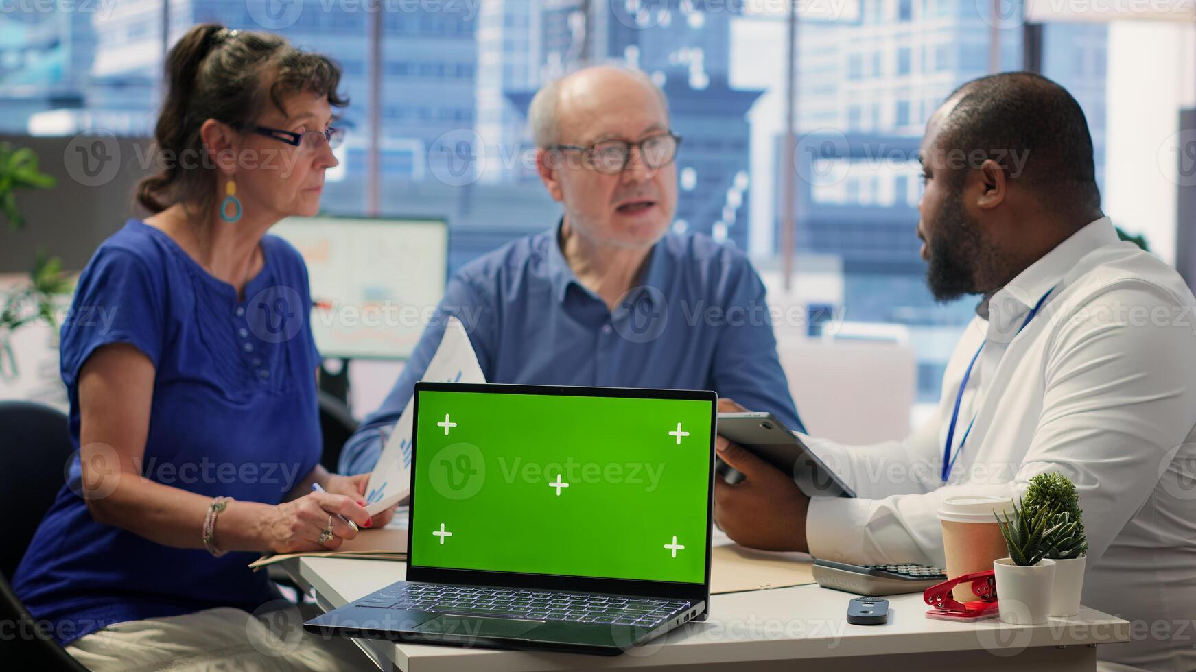 Broker helping old couple with retirement plans options at a financial counseling meeting, working with chroma key display. Elderly couple asking insurance expert about financial options. Camera A. photo