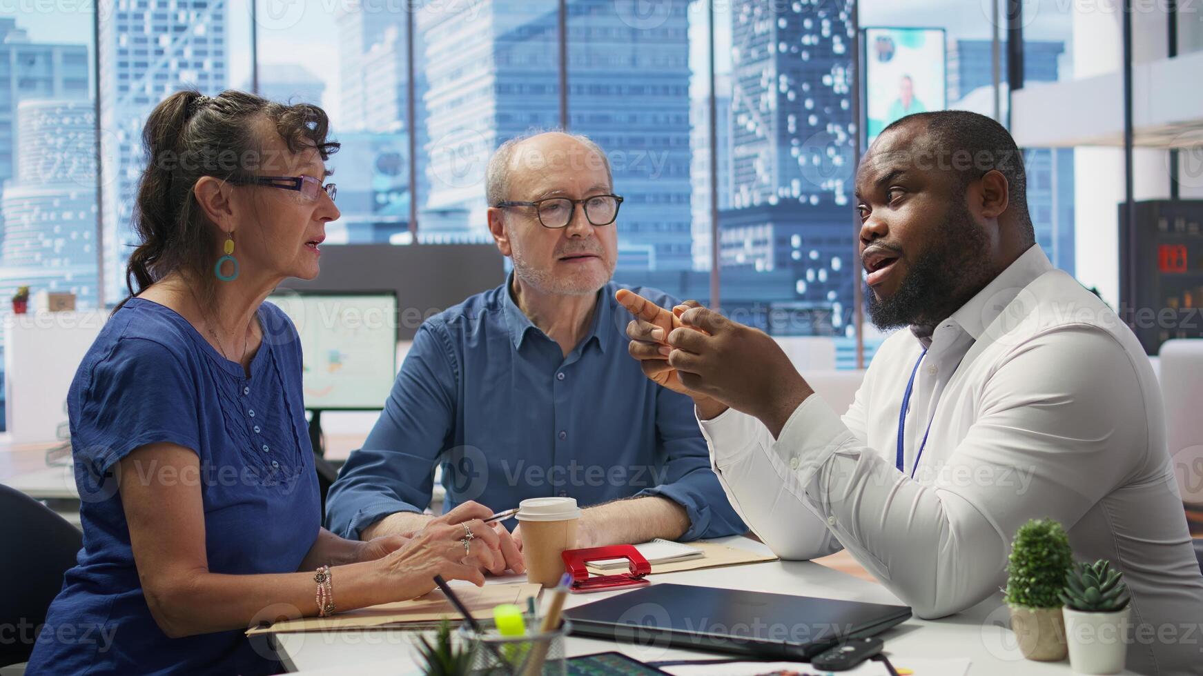 Elderly pair meeting with a financial expert to explore comprehensive retirement strategies, including savings, pension plans and investments. Looking into options to secure finances. Camera B. photo