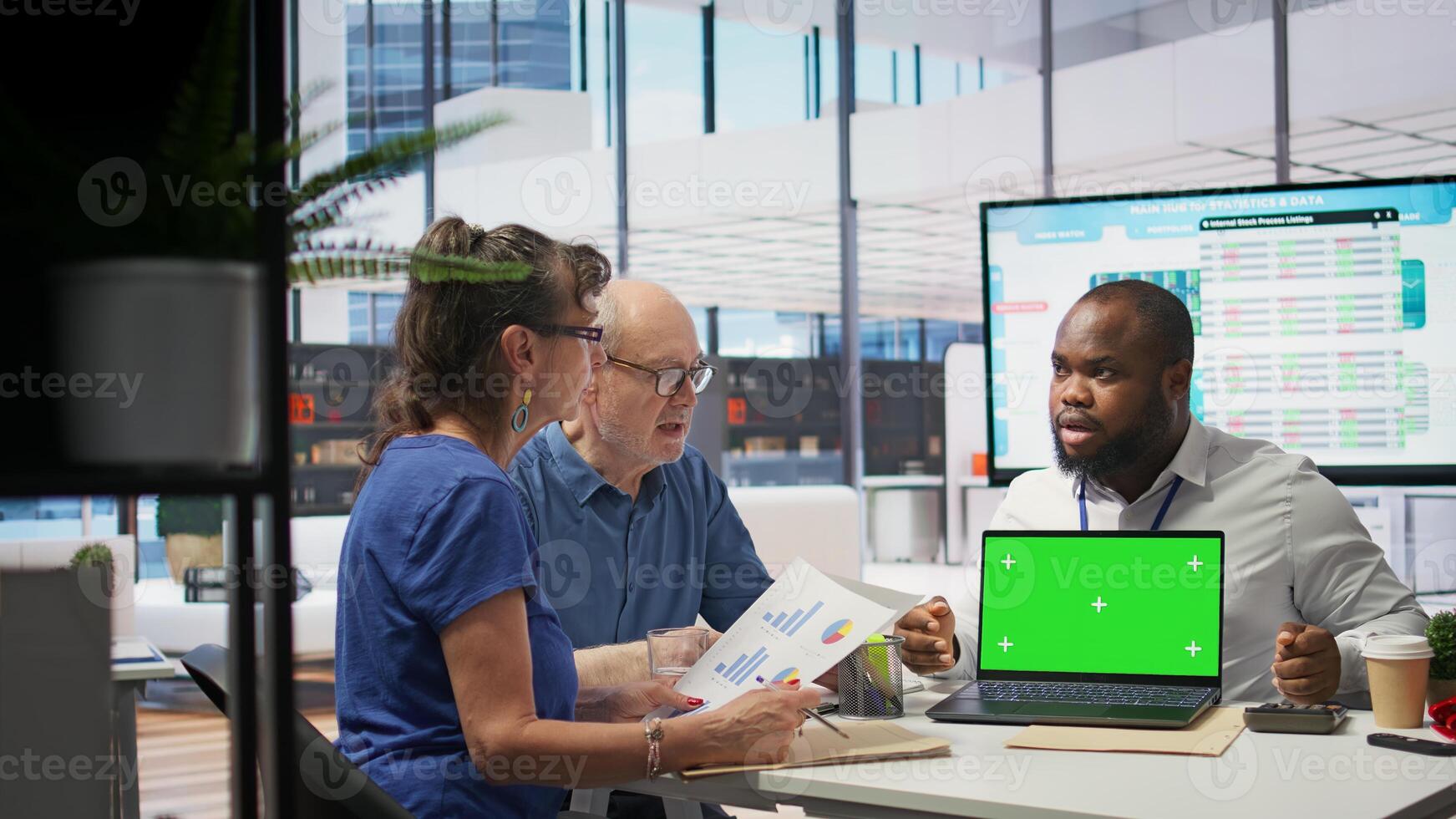 Banker offering pension plans options to elderly people next to isolated mockup screen, choosing the perfect retirement planning. Senior couple consulting life insurance adviser. Camera B. photo