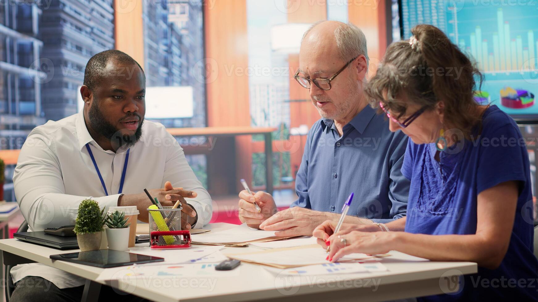 Elderly woman shaking hands with financial broker in modern office, reaching an agreement and signing contract for a new retirement plan. Satisfied client thanking advisor for guidance. Camera A. photo