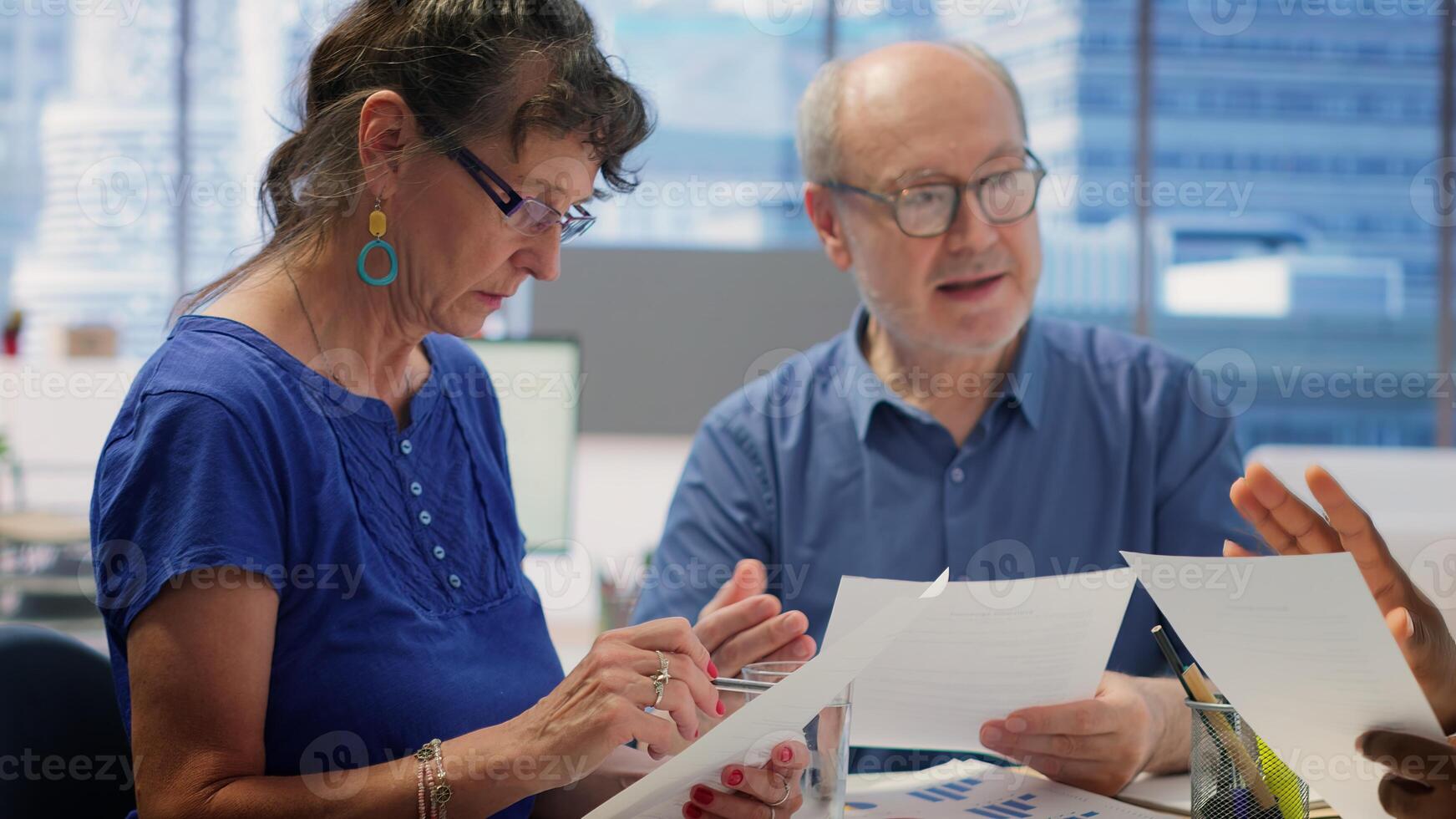 Mature couple meeting with a financial expert to develop a detailed retirement plan, focusing on savings and long term financial security. Clients discussing with broker in office. Camera A. photo