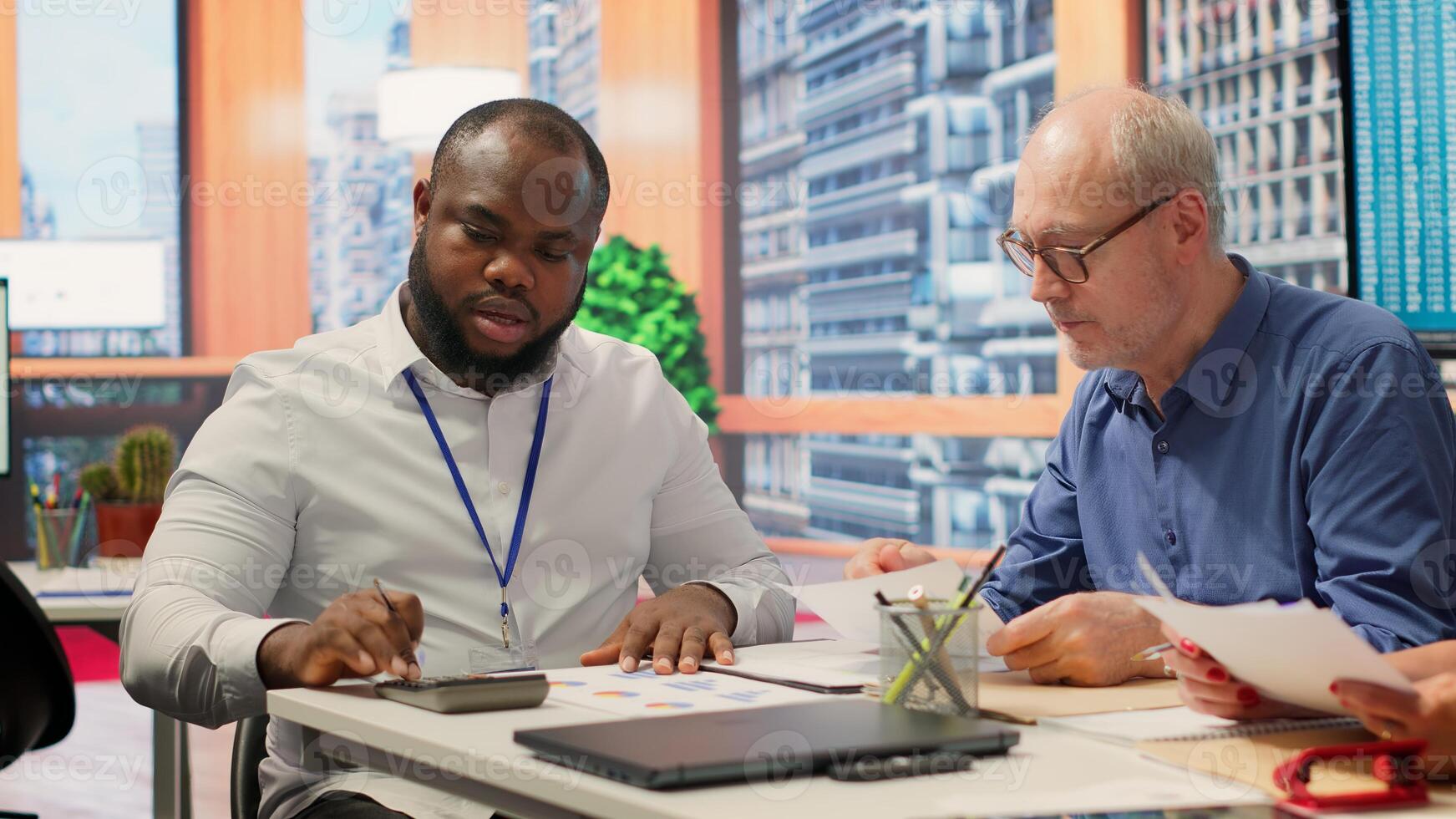 Senior woman reads the new retirement plan contract in a meeting with broker, agreeing to agency terms and securing their pension for the future. Life insurance financial options. Camera A. photo