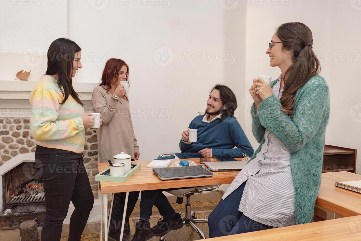 Four co-workers have coffee in the office, chat and have fun, taking a break. photo