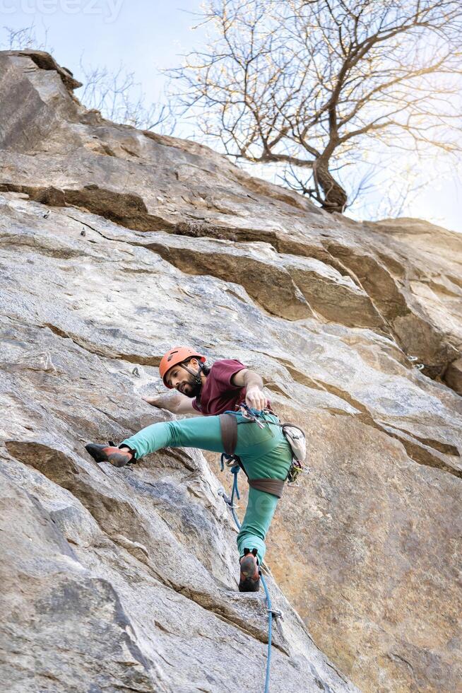 Young man climbing a challenging route on a cliff. Extreme sport. photo