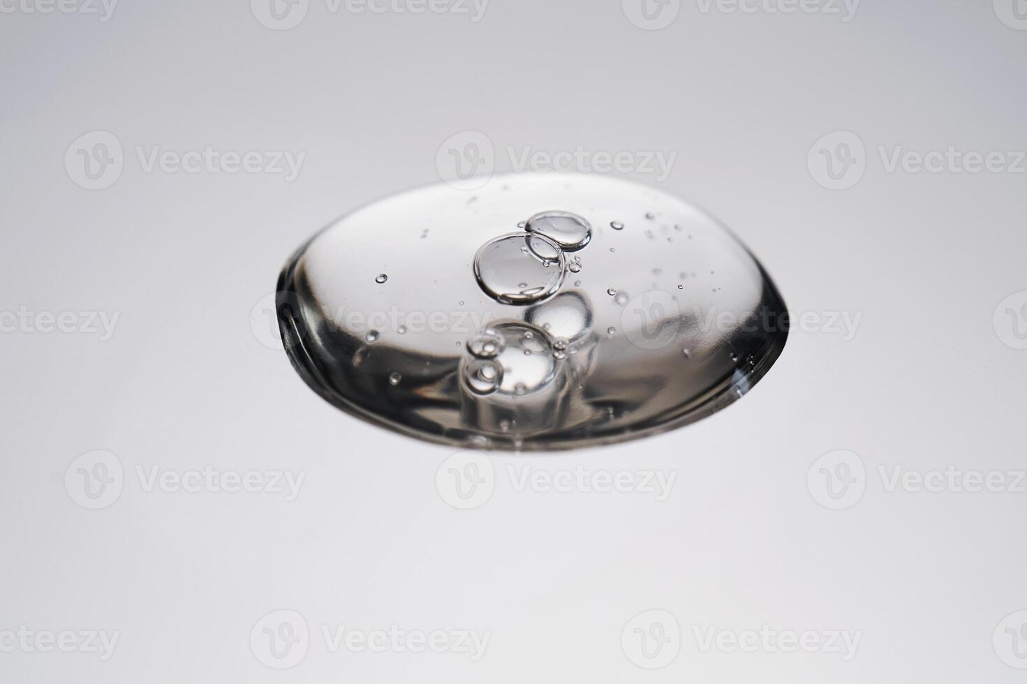 A drop of cosmetic product with bubbles on a gray background. photo