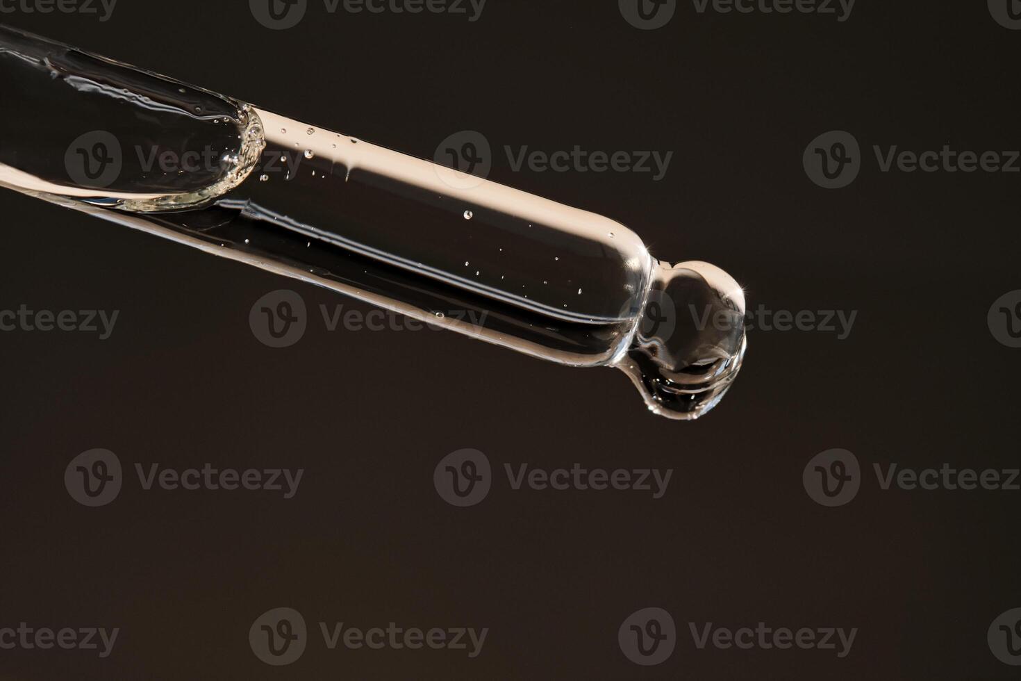 Pipette with serum on a dark beige background. photo