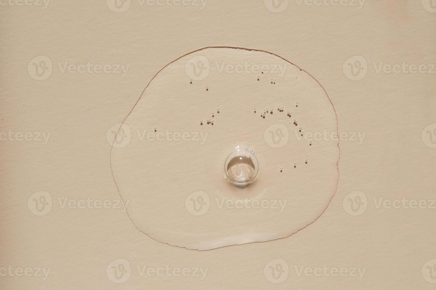 A drop of serum with bubbles on a beige nude background. photo