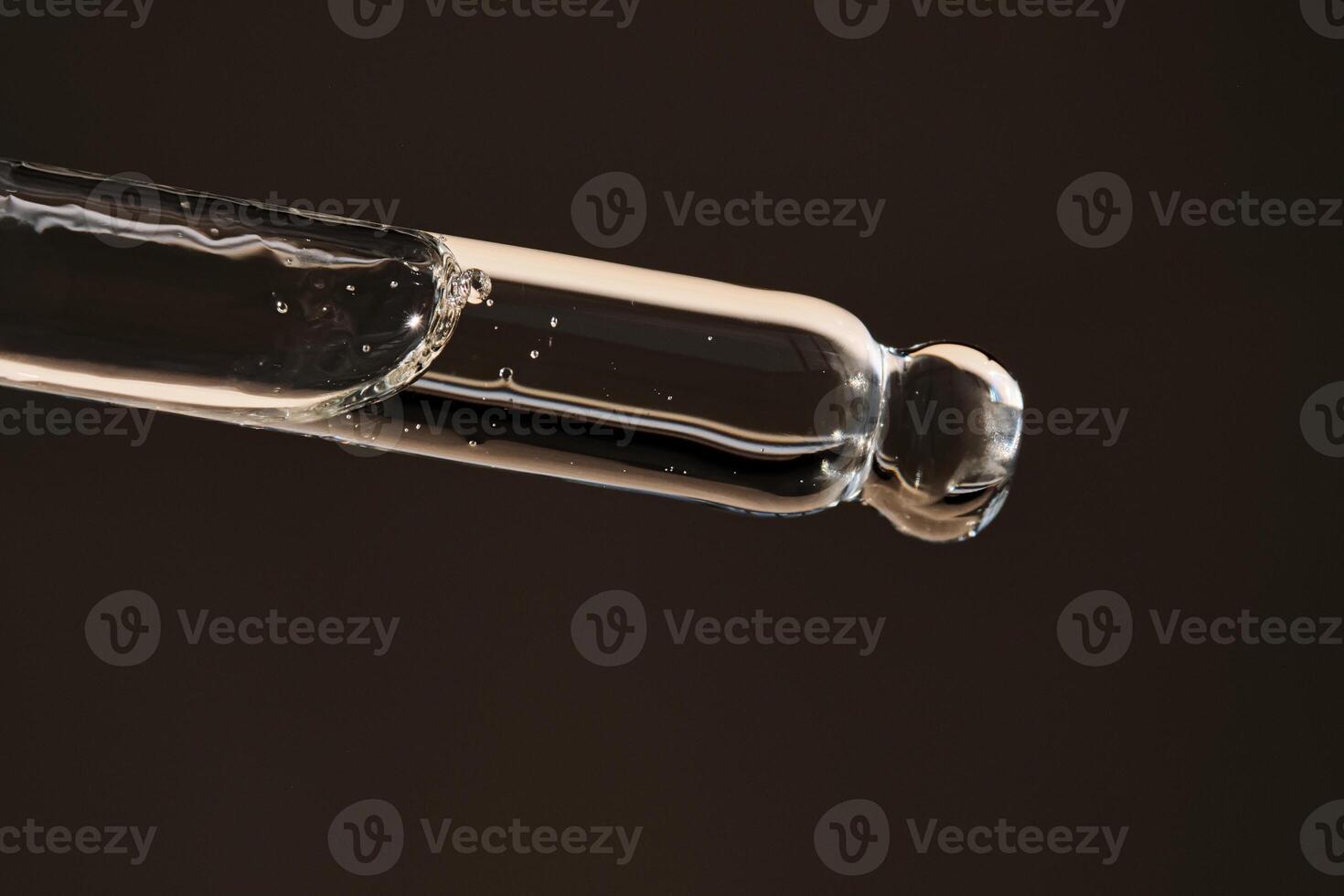Pipette with serum on a dark beige background. photo