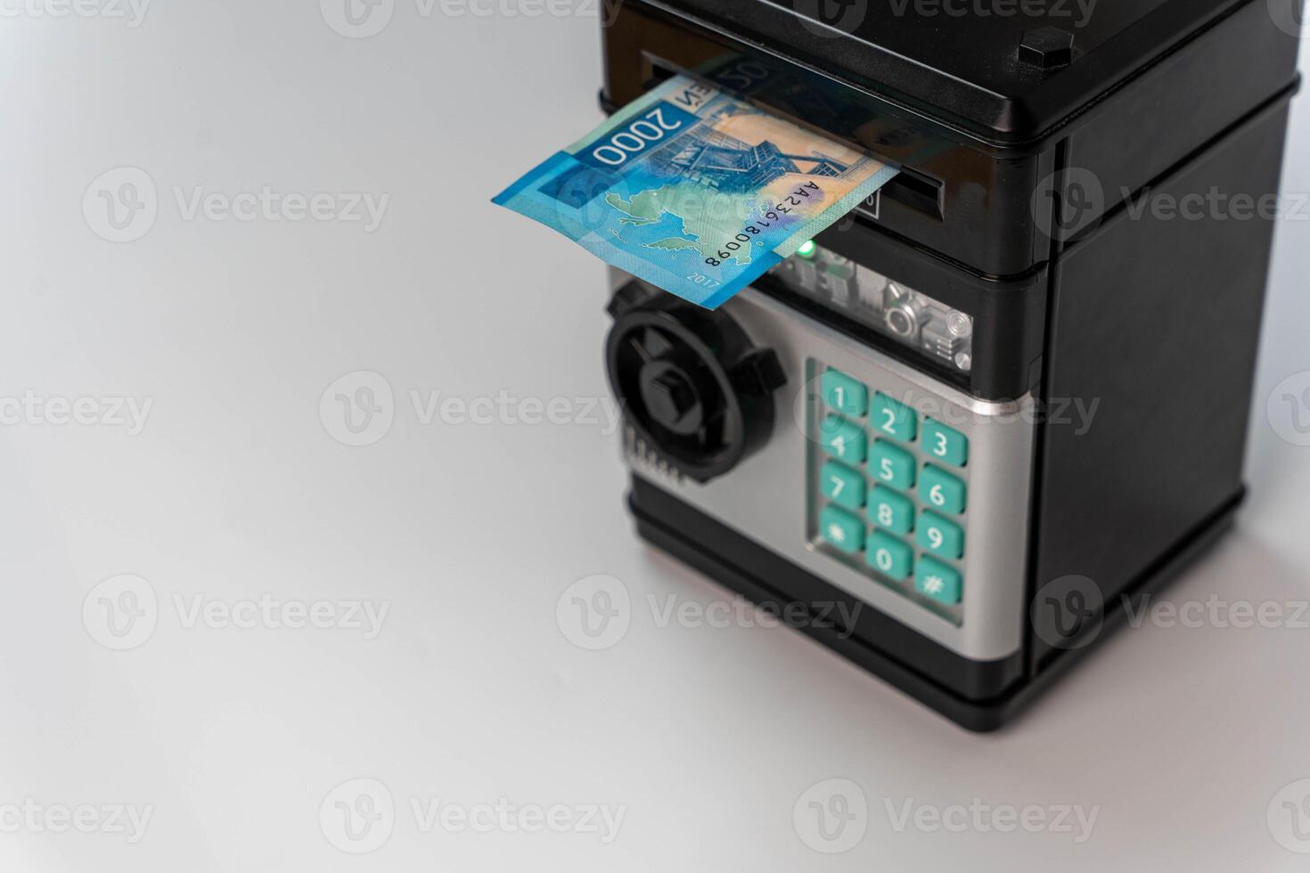 A two thousand ruble bill being placed into a toy safe photo