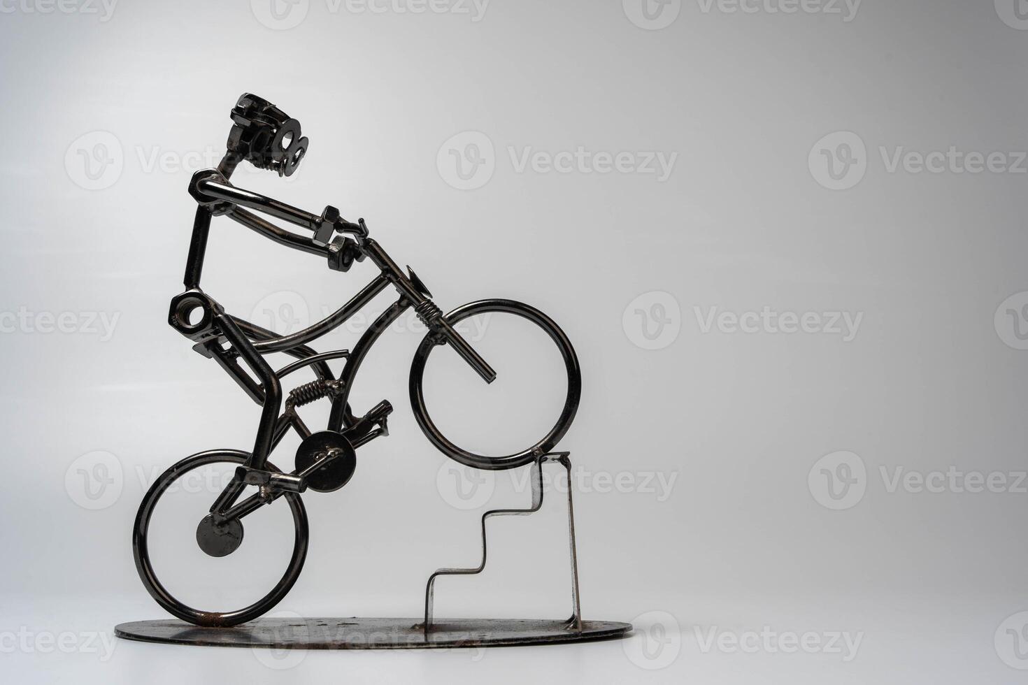 Metal sculpture of a cyclist performing a wheelie on a set of stairs photo
