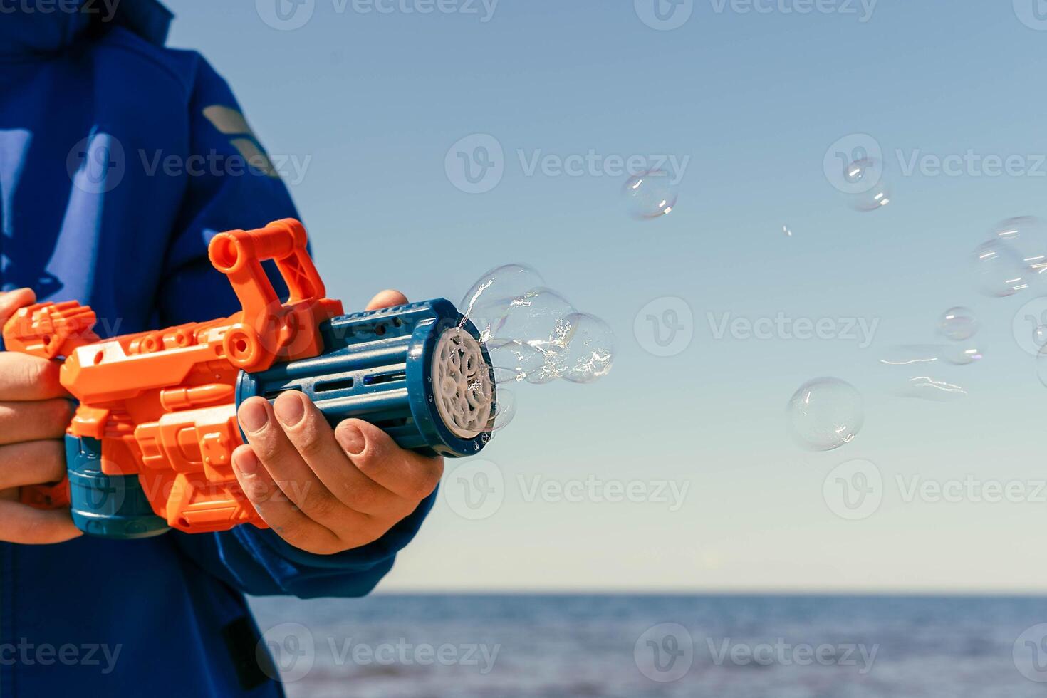 A boy holds a bubble gun and blows bubbles in the air photo