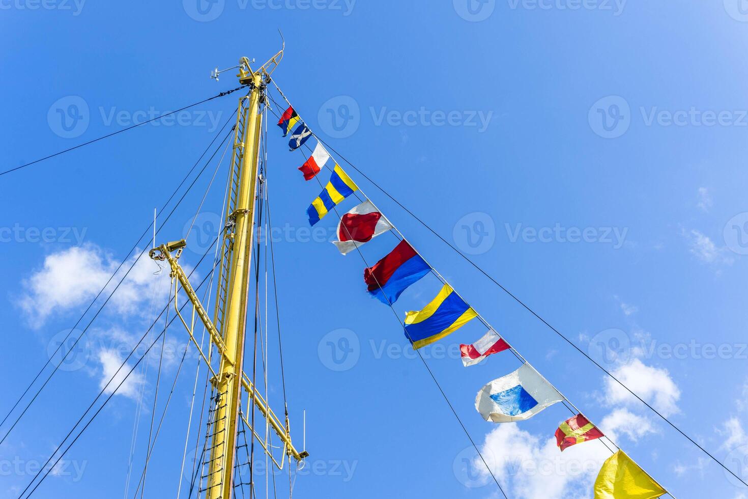 A close-up of a ship's mast with colorful signal flags flying photo