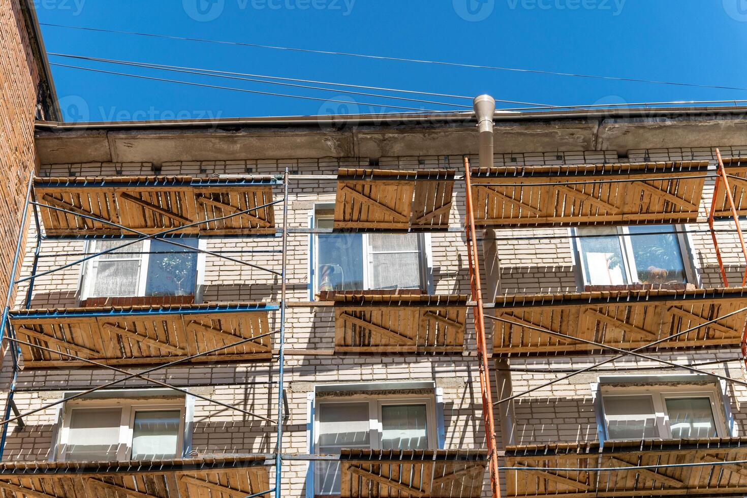 Scaffolding covers windows on a brick building under renovation photo
