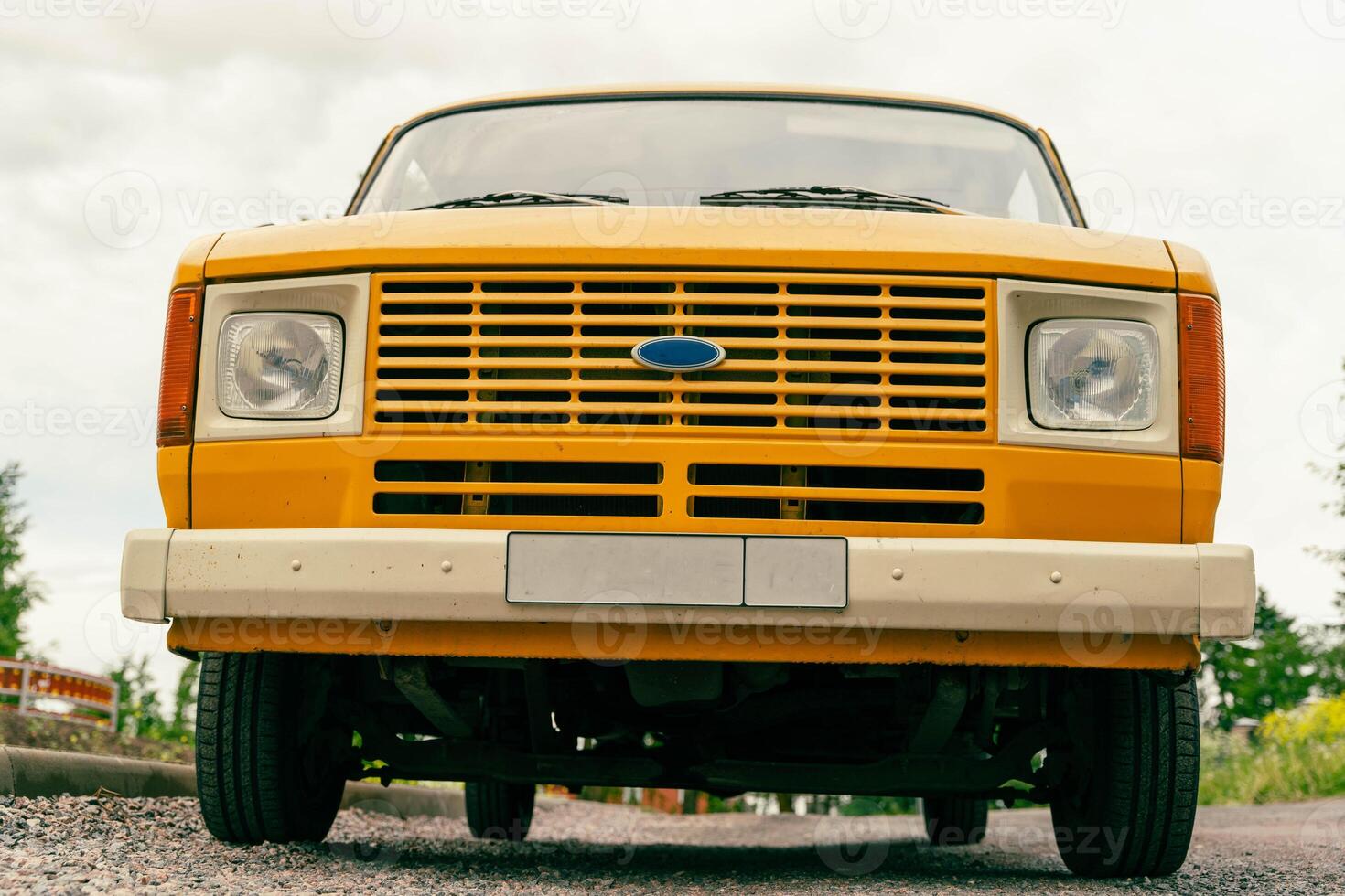 A yellow van is parked on a gravel road photo