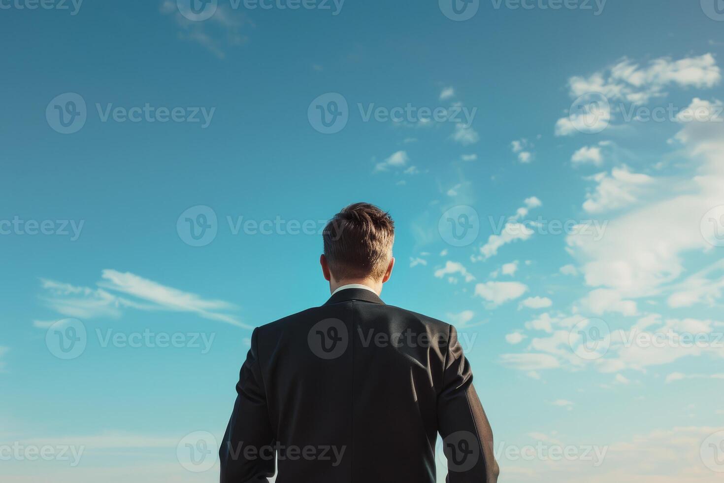 A man in a suit looks up at the sky with ambition, representing goals, determination, and aspiration photo
