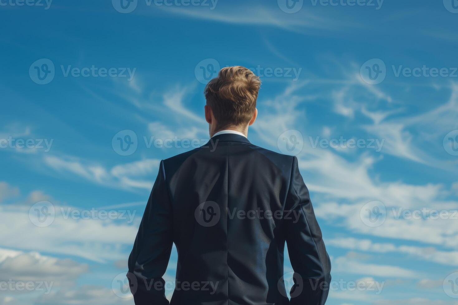 Businessman symbolizing ambition and success against clear blue sky, representing determination and achievement photo