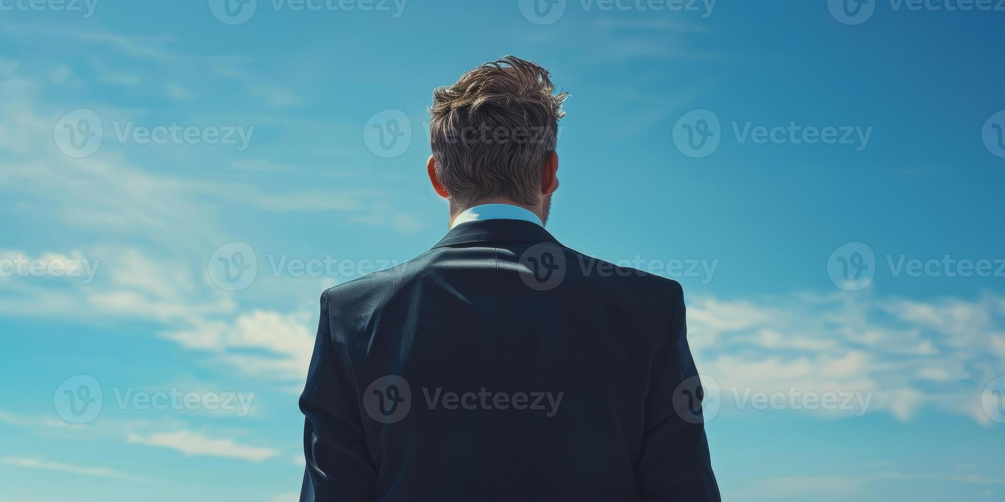 Rear view of a businessman in a suit looking at the sky on a sunny day, symbolizing ambition and future. photo