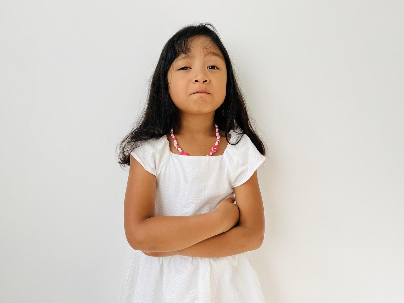 Negative human emotions, reactions and feelings. Isolated shot of moody displeased angry little girl crossing arms on her chest, pouting lips, having offended facial expression, being capricious photo