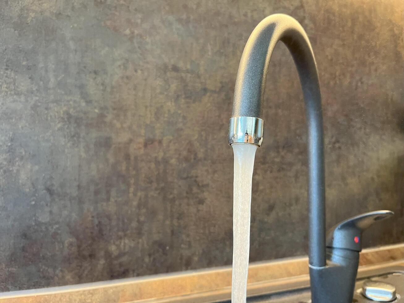A running tap with the water running in the kitchen. The tap lets the water run, nobody. Don't waste water. photo