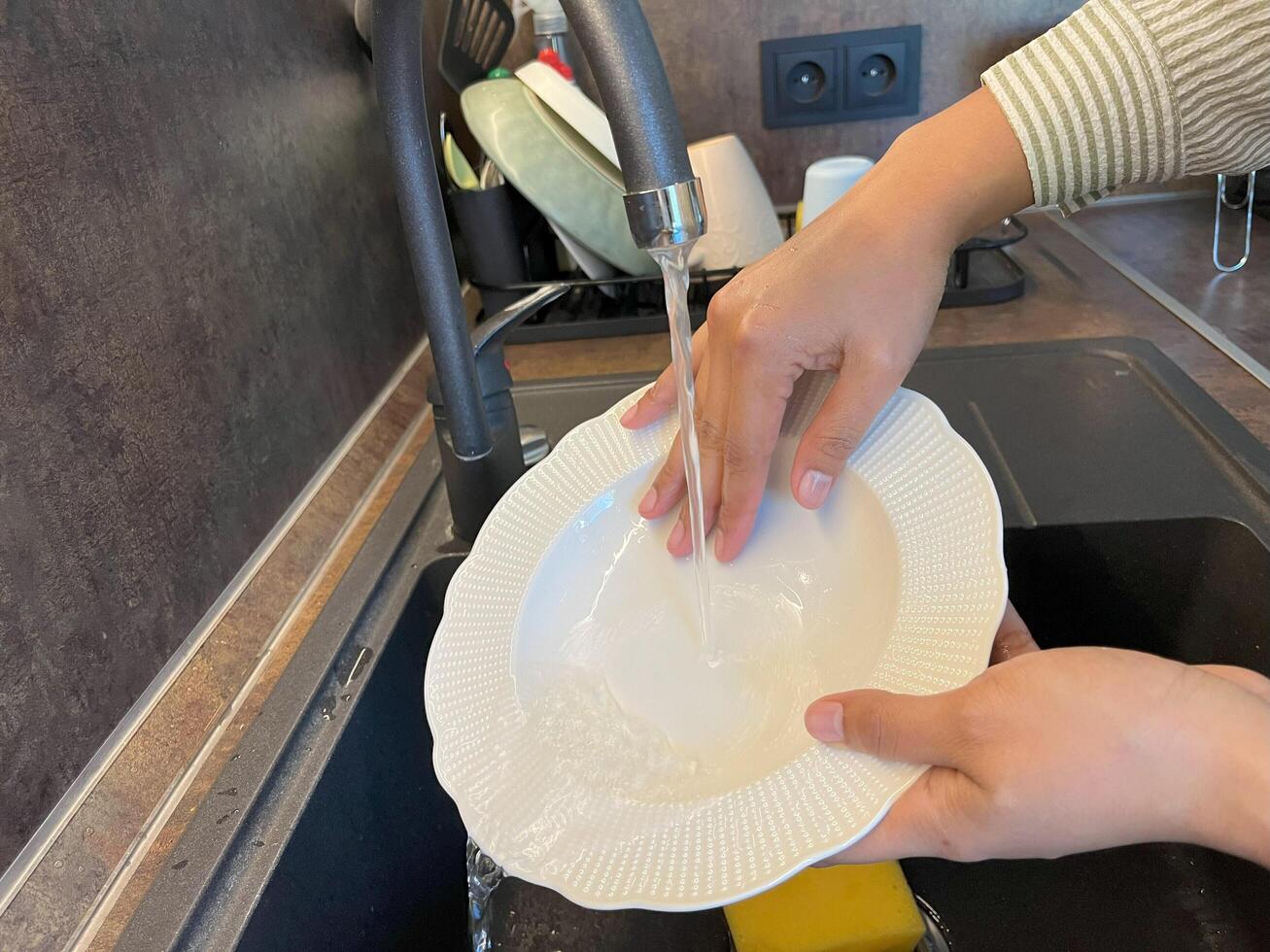Close up of woman housewife is doing the dishes at home kitchen by using wash sponge and dishwashing soap. Clean the plate photo