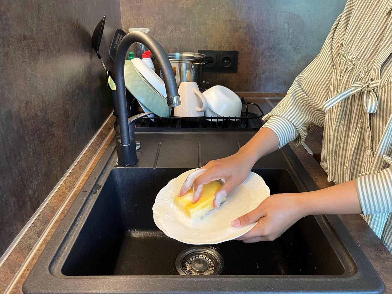 Close up of woman housewife is doing the dishes at home kitchen by using wash sponge and dishwashing soap. Clean the plate photo