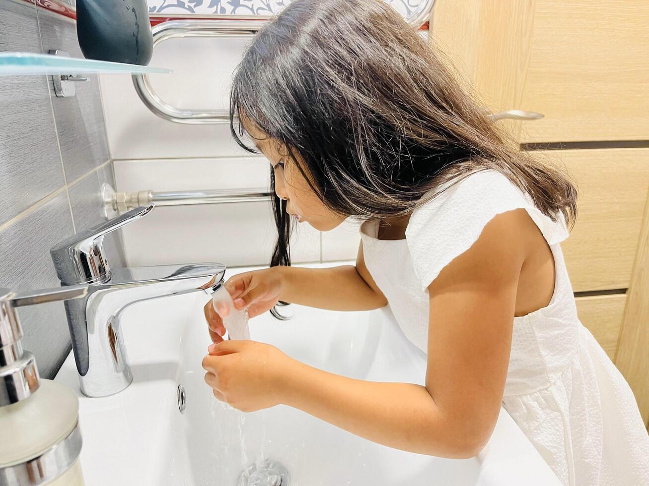 A five year old girl is gargling her mouth after brushing her teeth in bathroom. Morning routine. Hygiene. Healthy lifestyle photo