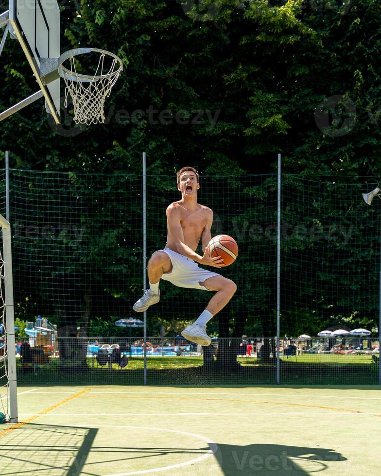 young caucasian basketball player athlete in action playing field on a sunny summer day photo