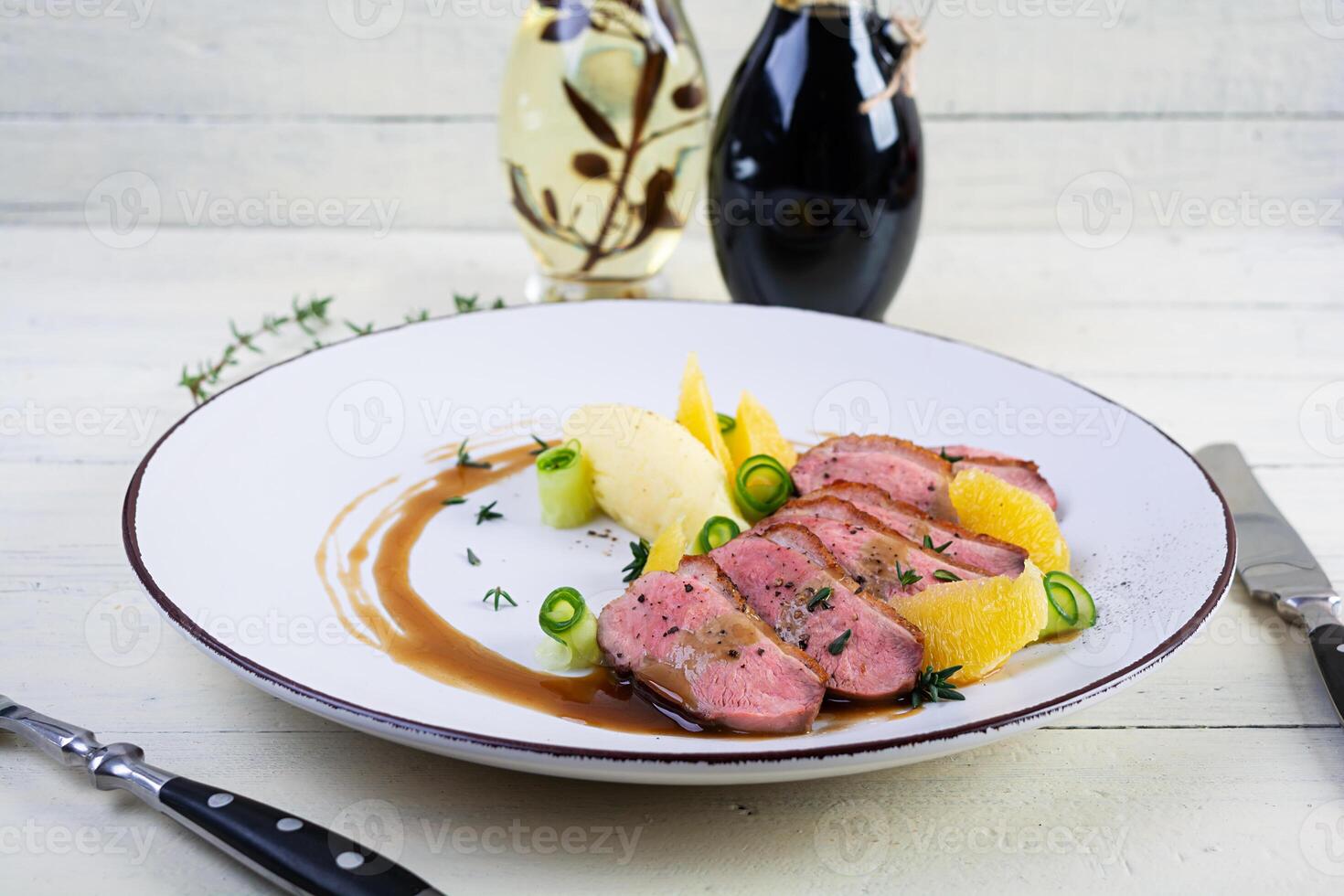Roast duck fillet with mashed potato and orange sauce on wooden background photo