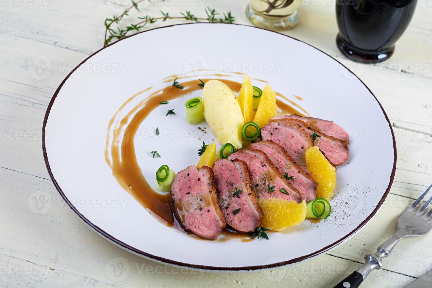 Roast duck fillet with mashed potato and orange sauce on wooden background photo