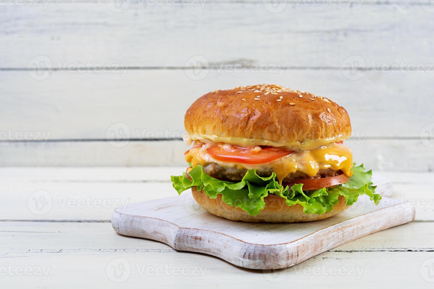 Delicious homemade burger with chicken meat. Cheeseburger on white wooden background photo