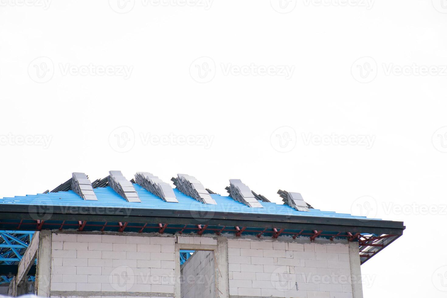 Gray roof of house under house building construction site against blue sky. New tile roof of home with spanish tiled roof at unfinished house construction, Preparation for laying roof tiles structure. photo