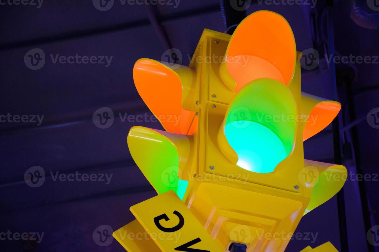 Neon traffic light sign and yellow frame with orange and green light on purple light background. Modern traffic light signs for decorating places and buildings. photo