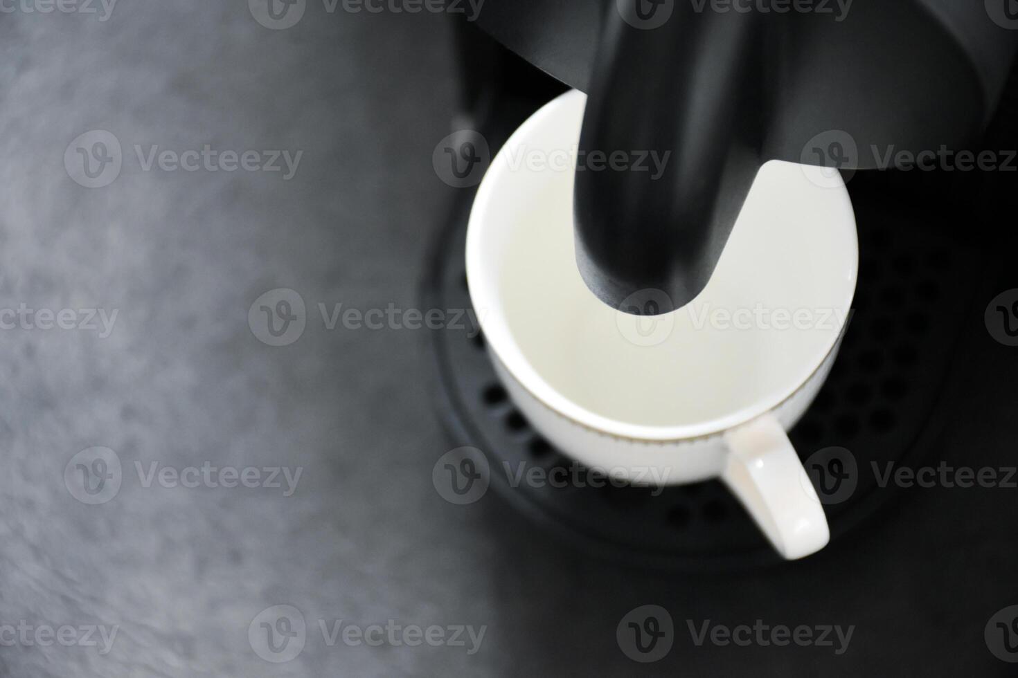 Top view of hot coffee machine preparing espresso coffee into white cups on black background. The espresso coffee machine with white glass cups for hot coffee. photo