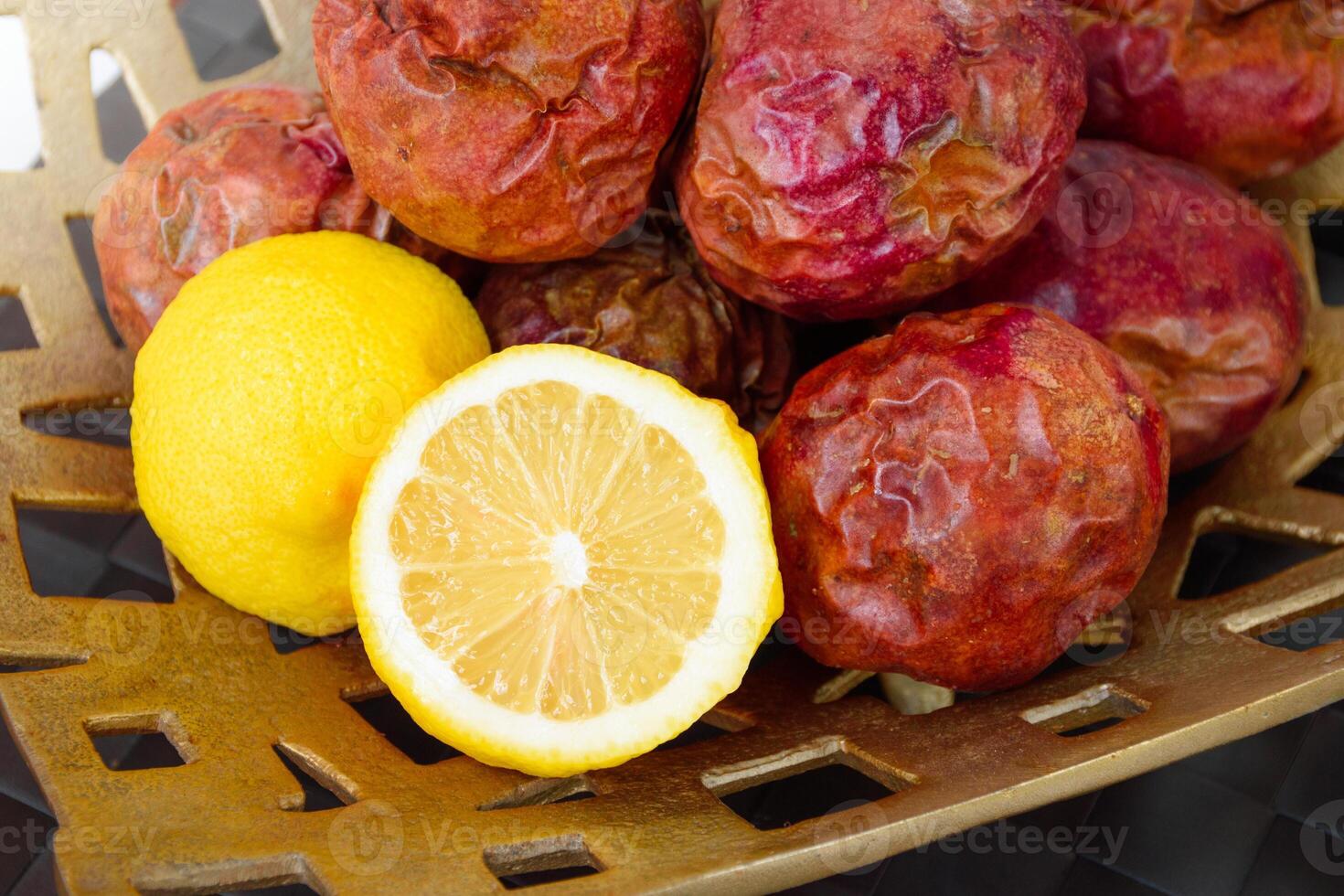 Close-up of yellow lemons and passion fruit showing the beautiful pattern of citrus fruits in a golden basket placed on a white wooden table. Cut lemon and passion fruit in half. photo