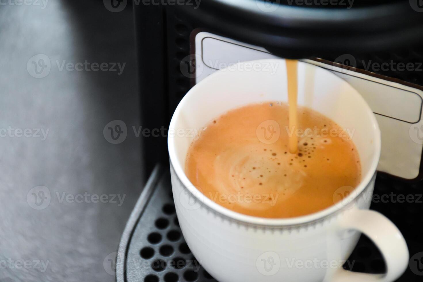 Close up of a espresso coffee machine pouring coffee into a white glass to prepare espresso on a black background. The espresso machine is preparing an Americano for your morning coffee. photo