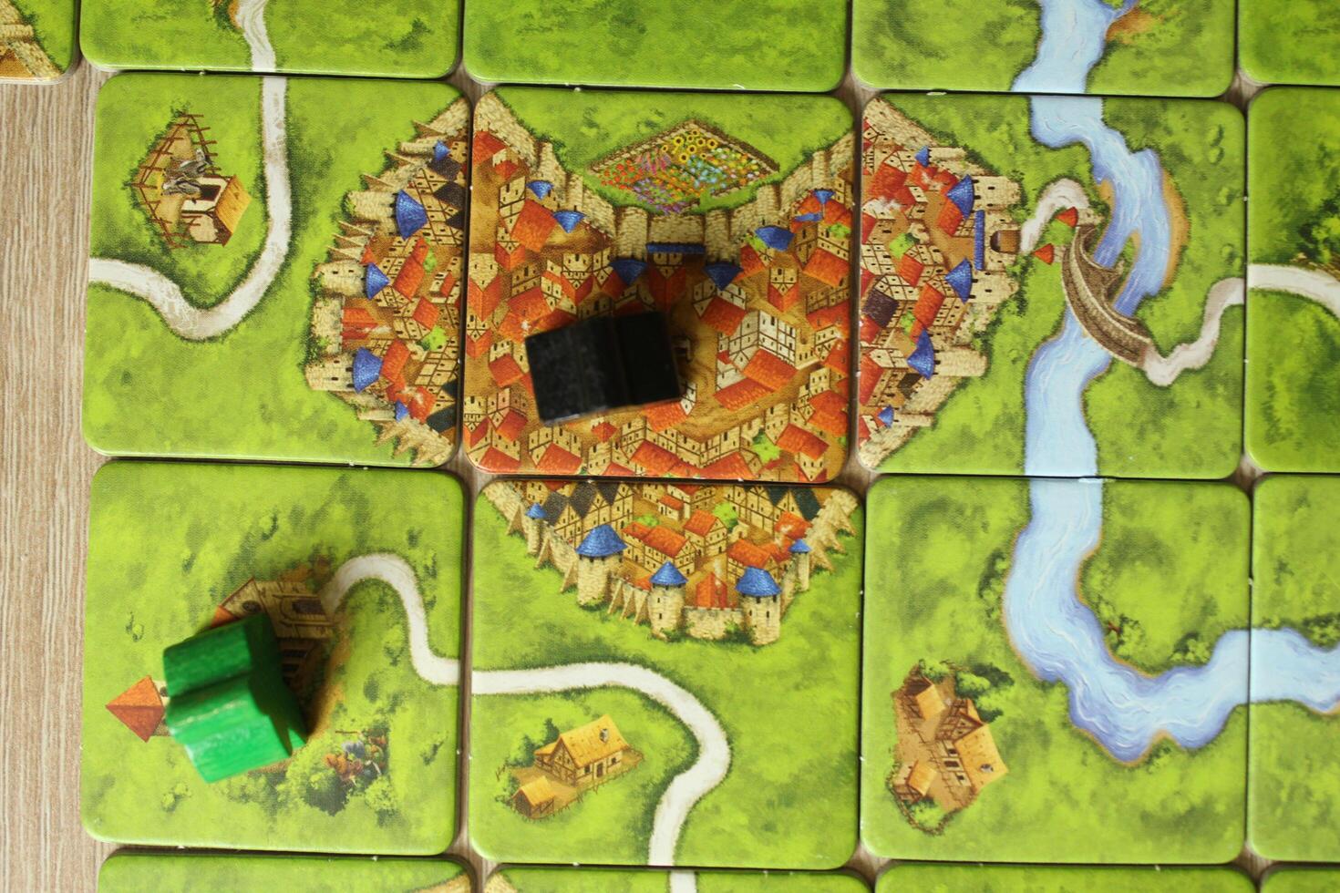 board game carcassonne meeples of different colors green black on the map top view of the rules of occupied objects of the city of the monastery. Score Points photo