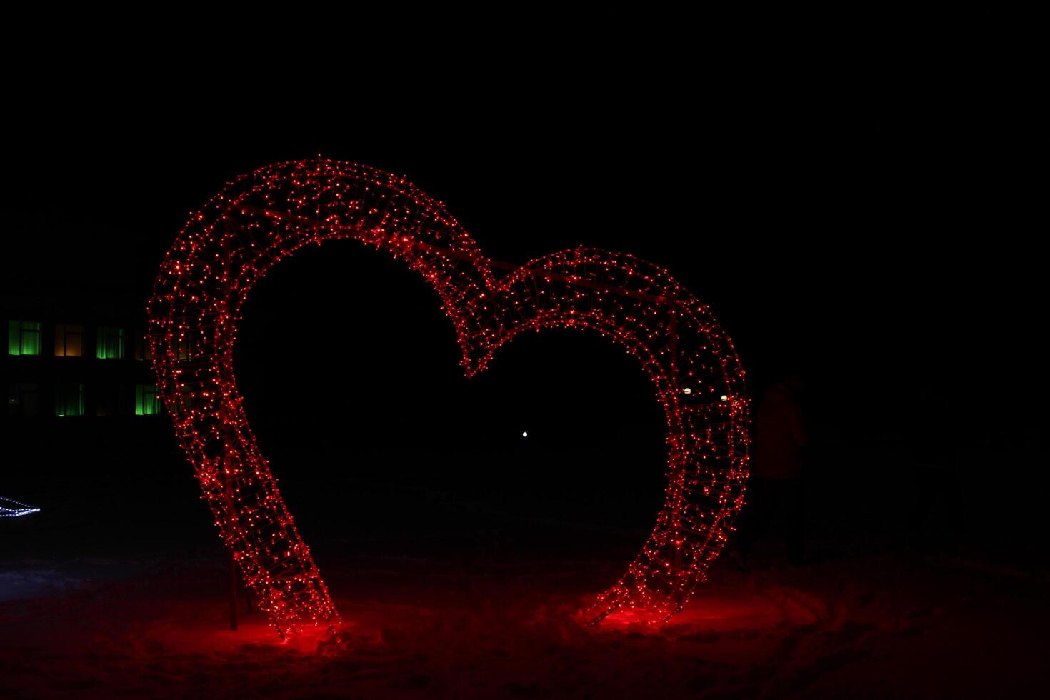 Christmas Figure Illumination Red Heart at Night. Festive atmosphere neon photo zone