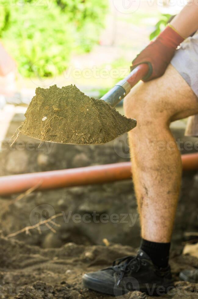 Guy is digging ground. Man with shovel. Digging up soil. Work on land. High quality photo