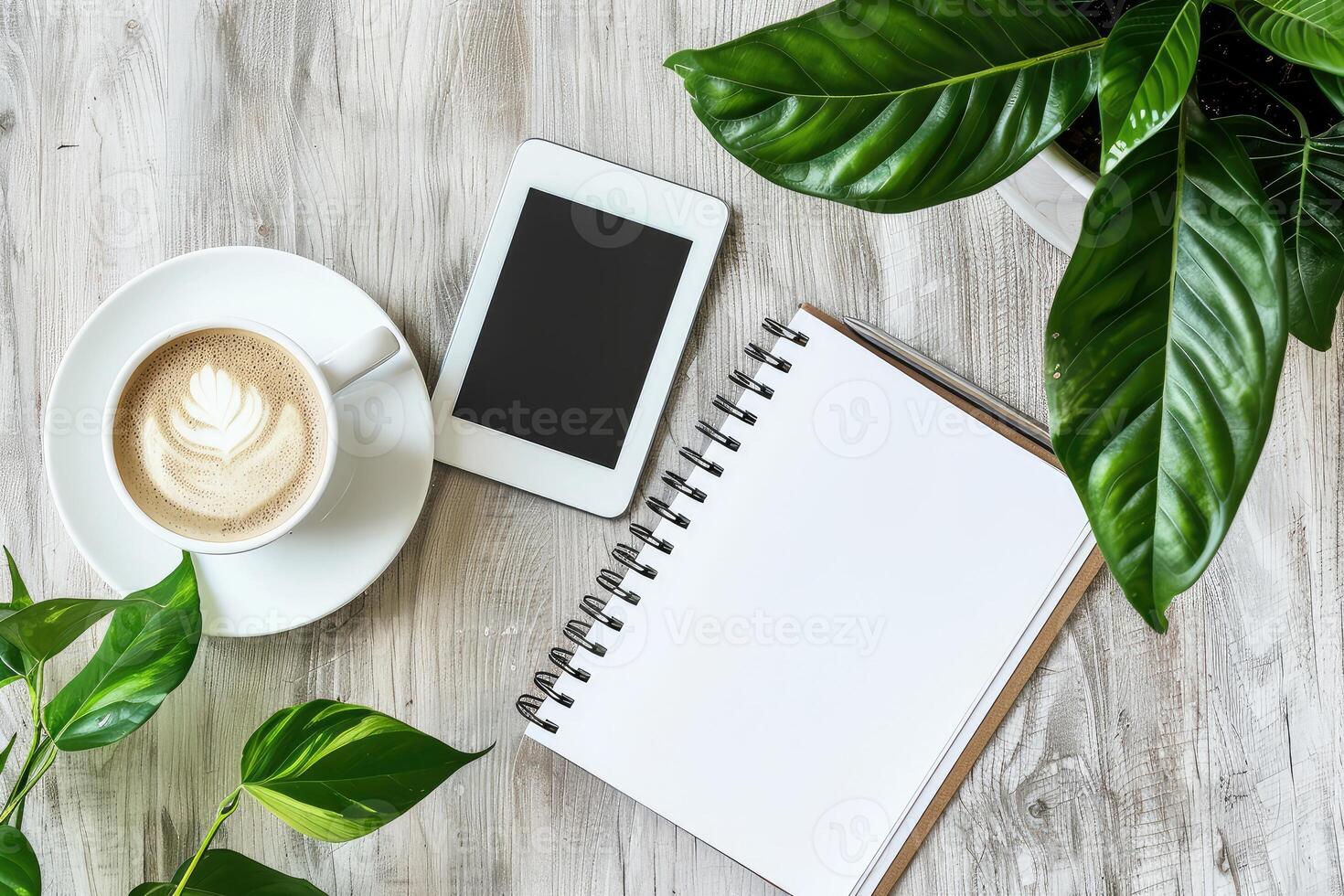 Modern workspace home office desk table with blank spiral notebook, digital tablet , cup of coffee and green plant leaves. Top view, copy space photo