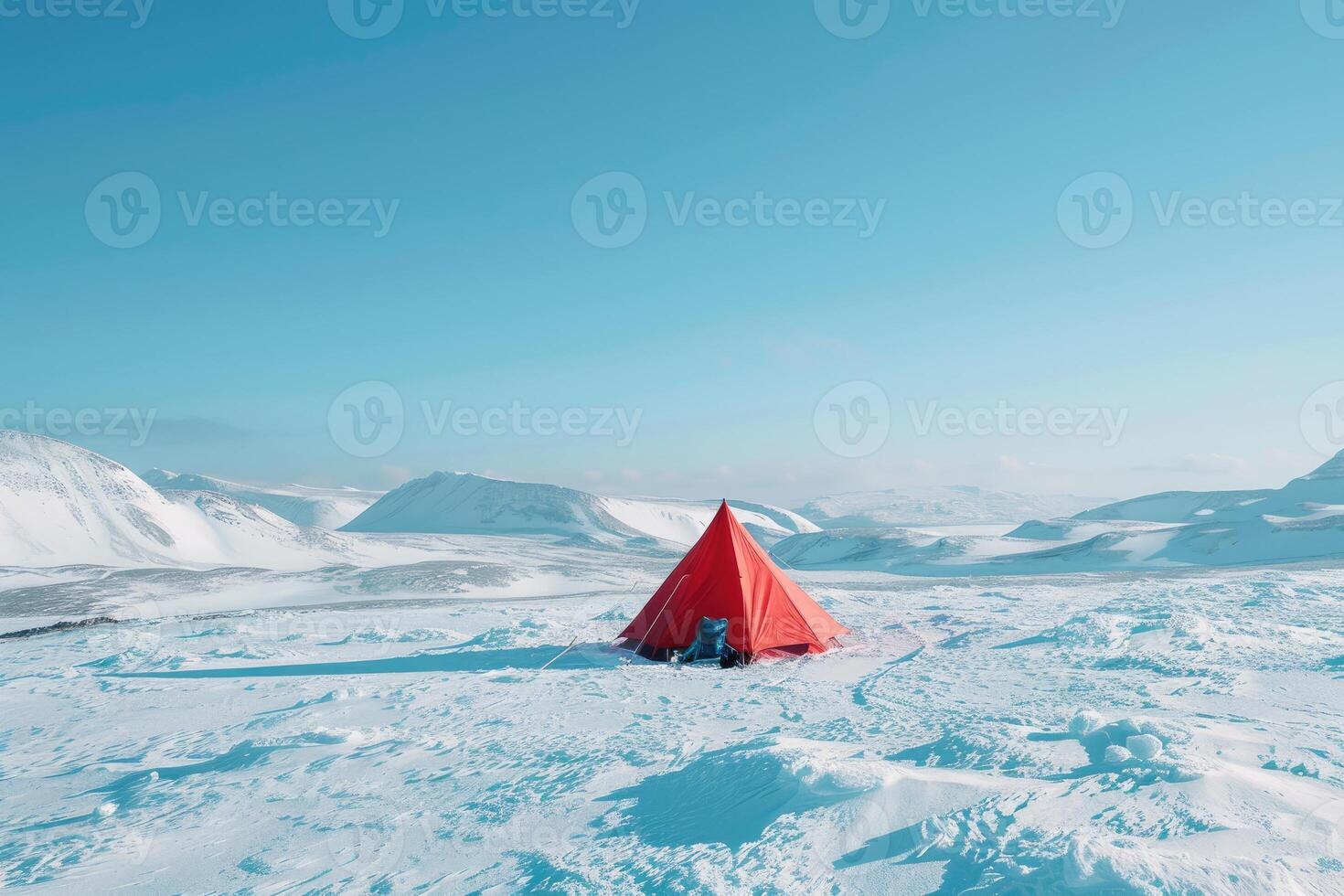 A red tent set against a backdrop of vast snowy mountains under a clear blue sky. photo