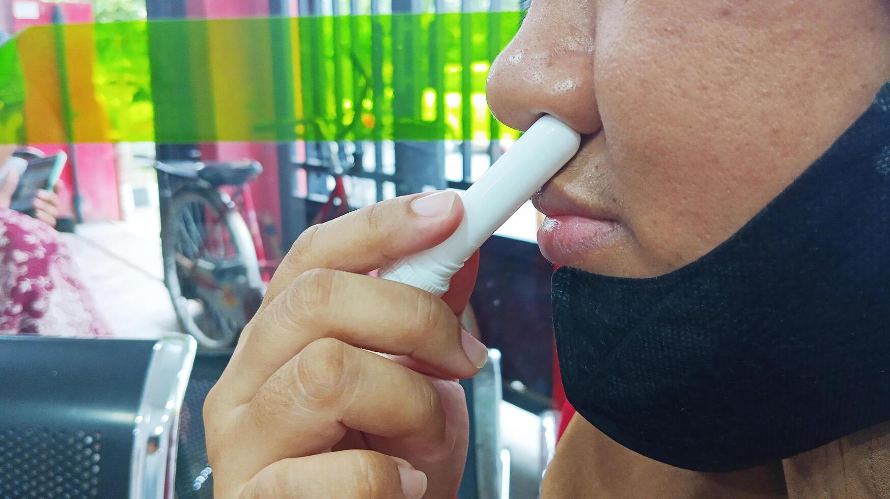 Semarang, Indonesia - March, 2024 - Asian woman using nasal stick inhaler photo