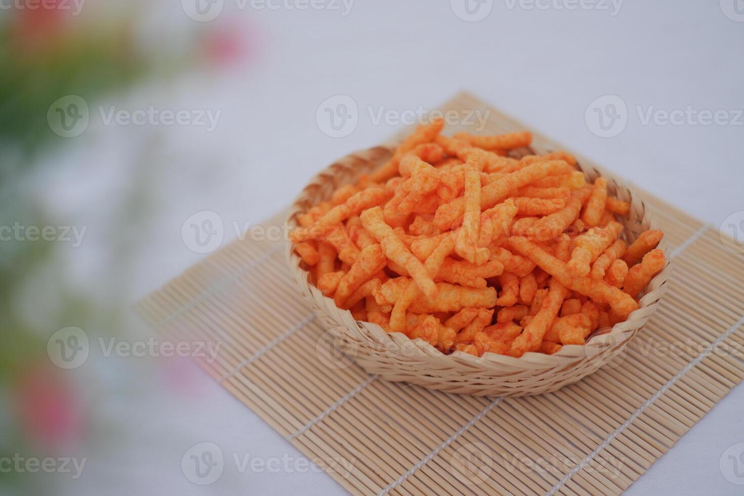 Crispy Corn Puffs in rattan basket on bamboo mat. Selective focus. photo