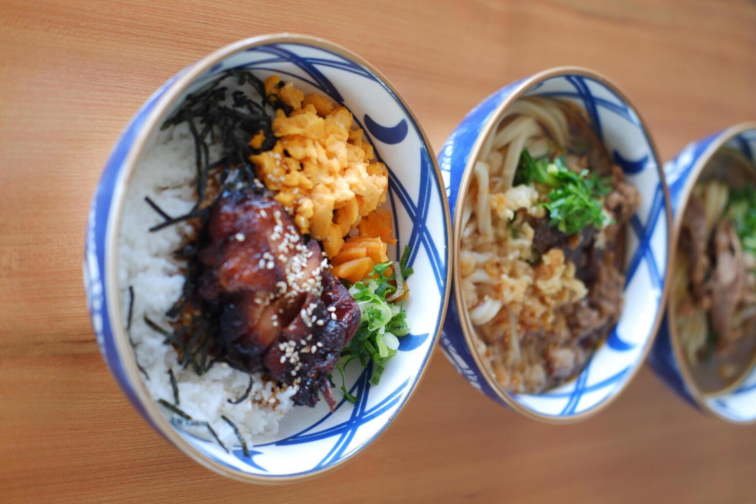Each bowl contains different ingredients such as meats, vegetables, and rice, garnished with green herbs photo