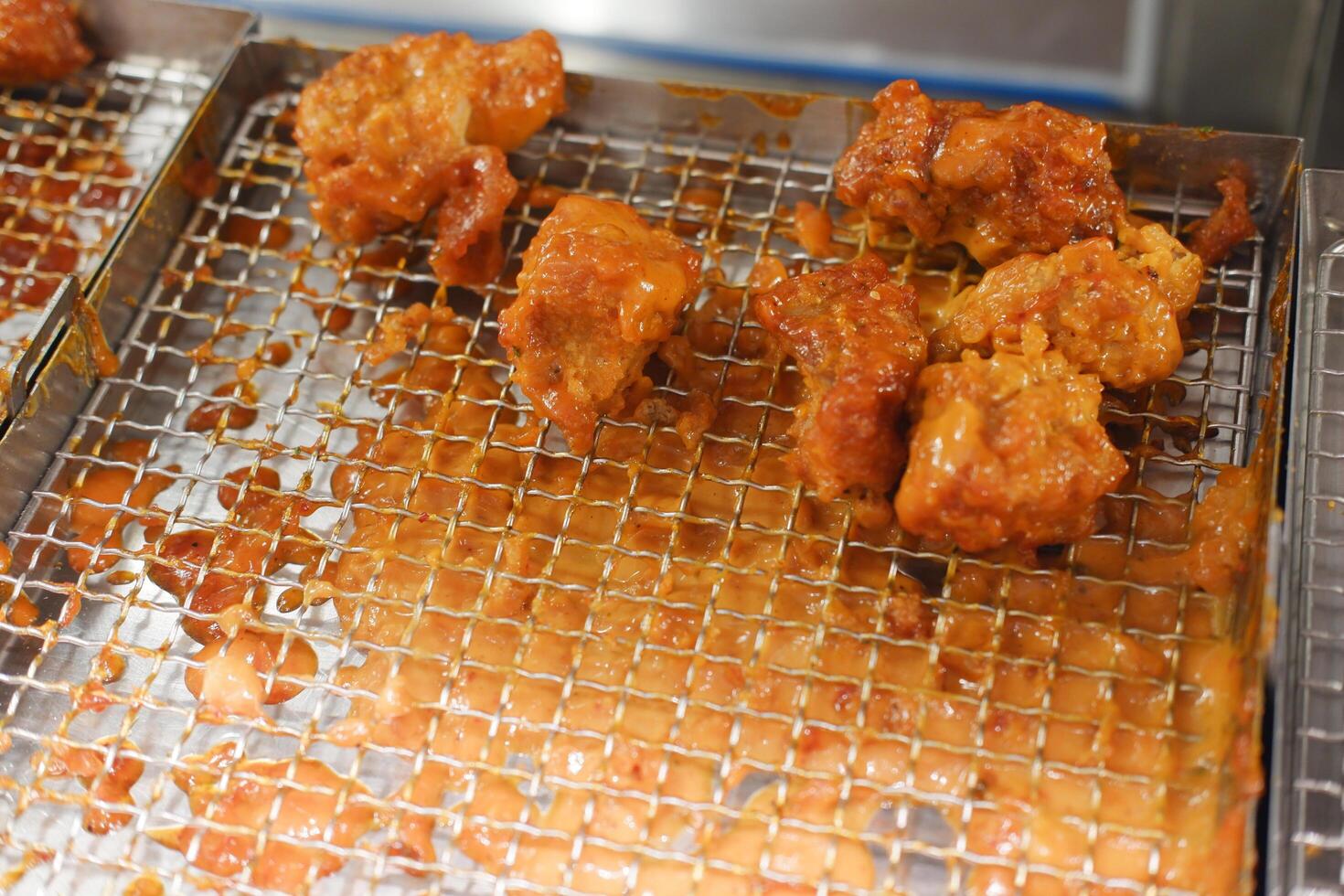 crispy fried chicken pieces coated with a reddish sauce resting on a metal wire rack photo