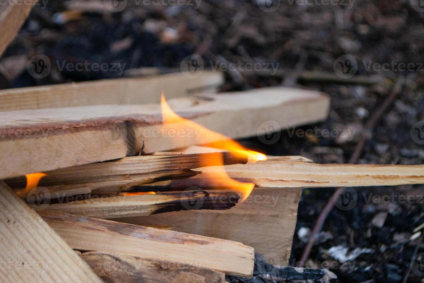 A fire burns in a campfire with a red fire in the background. photo