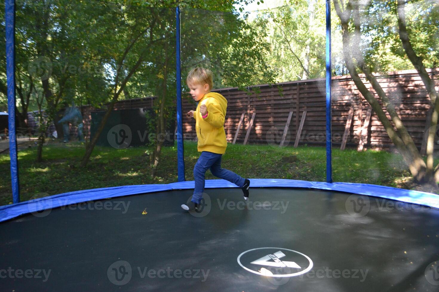 Little boy jumping and having fun on trampoline in amusement center for kids photo