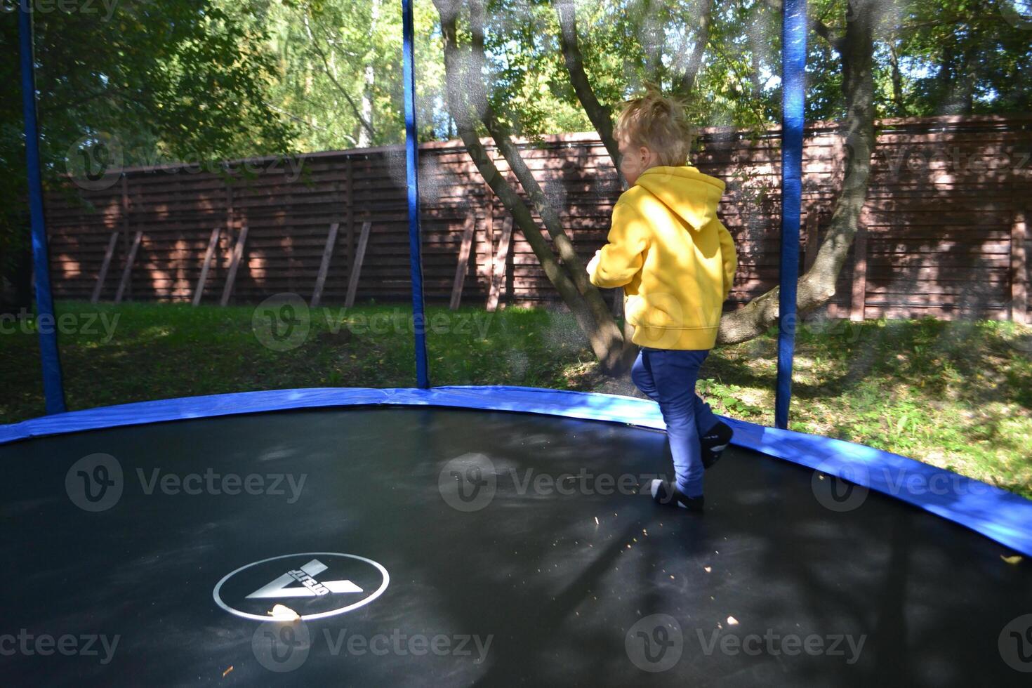 Little boy jumping and having fun on trampoline in amusement center for kids photo